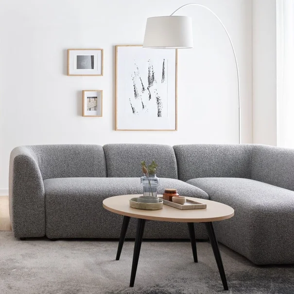 Minimalistyczny salon z szarą sofą i białymi ścianami.